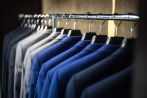 Cette photo représente une penderie sur laquelle est accroché plusieurs costumes