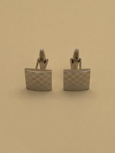 Cette image est des boutons de manchettes carrés damier